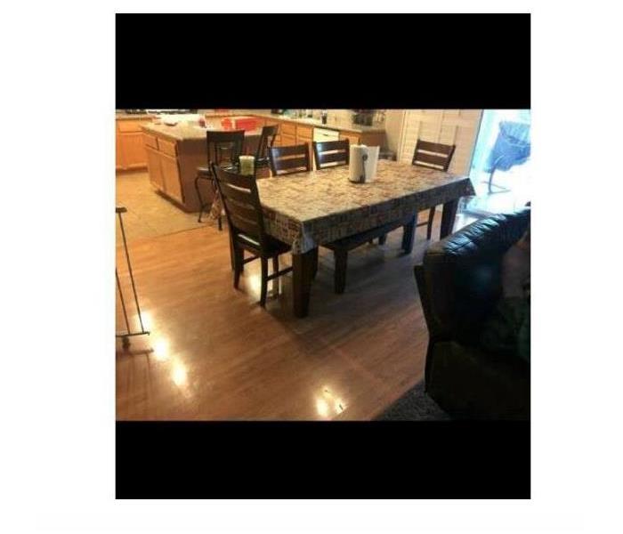 Kitchen with dining table and chairs with a water damaged hardwood floor.