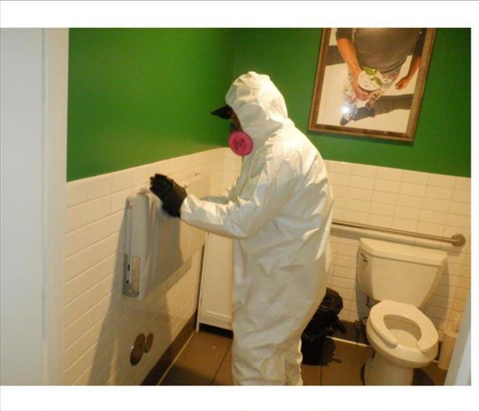Technician wiping down a restroom from water damage.