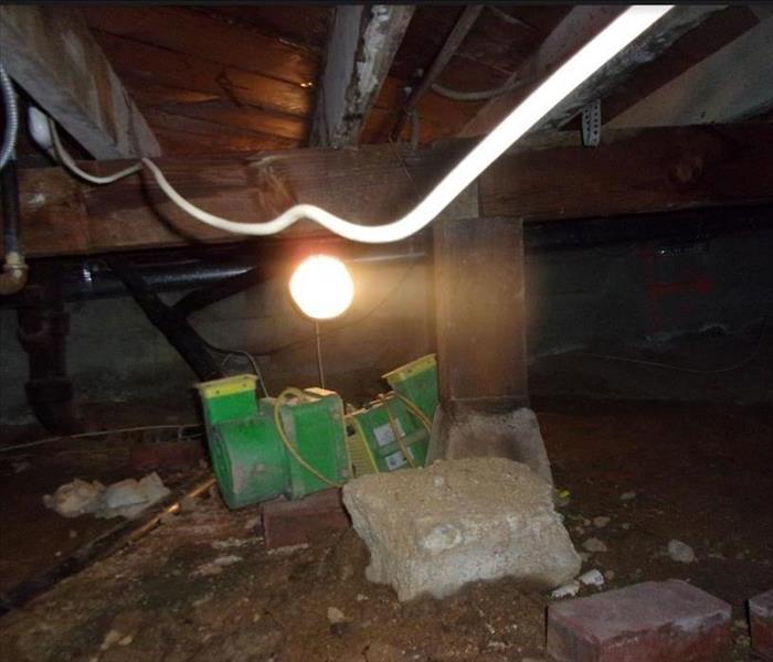 A restoration fan drying out a crawlspace with a light above.