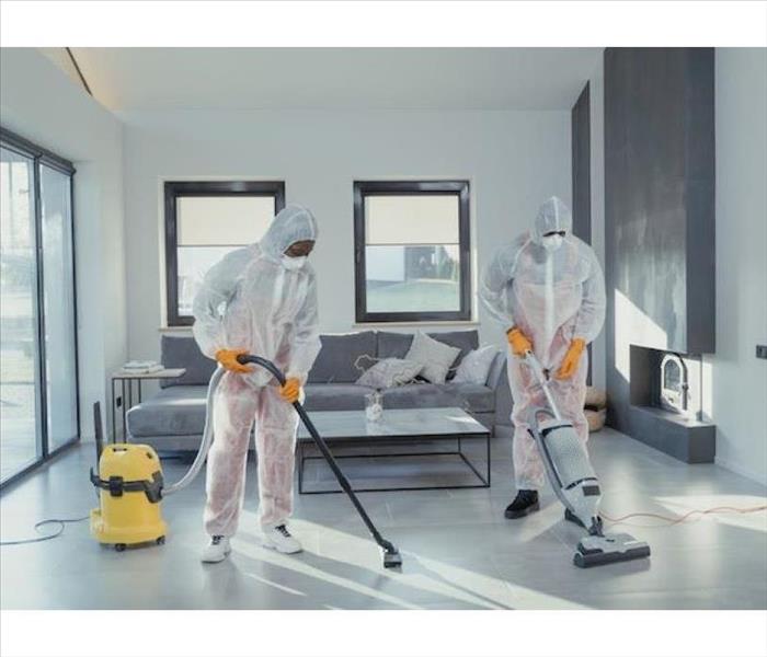 Two biohazard technicians cleaning a residential home.