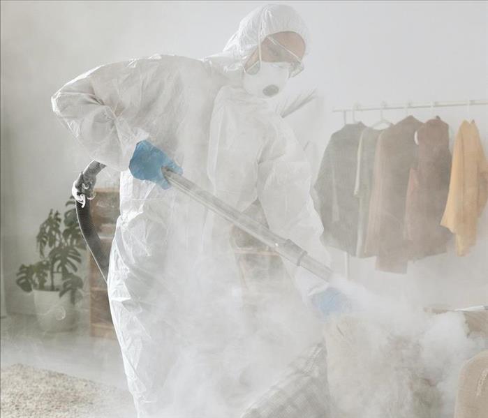 Technician in a PPE suit fogging a break room.
